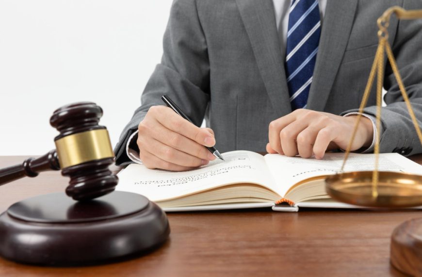 person writing in a book with a gavel on the table