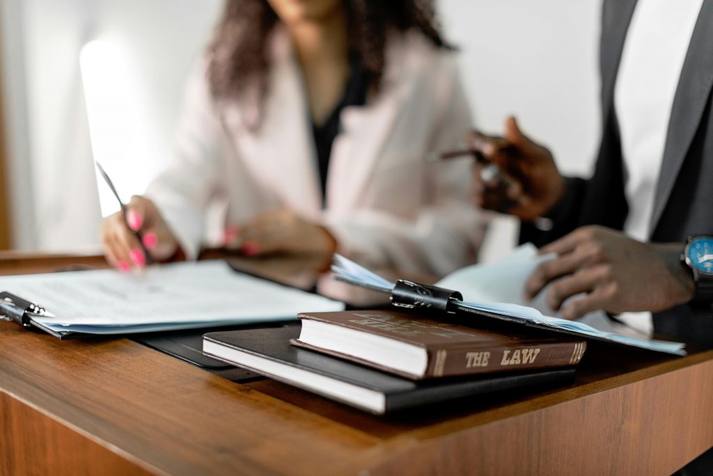 two professionals drafting contracts, with law books at the desk