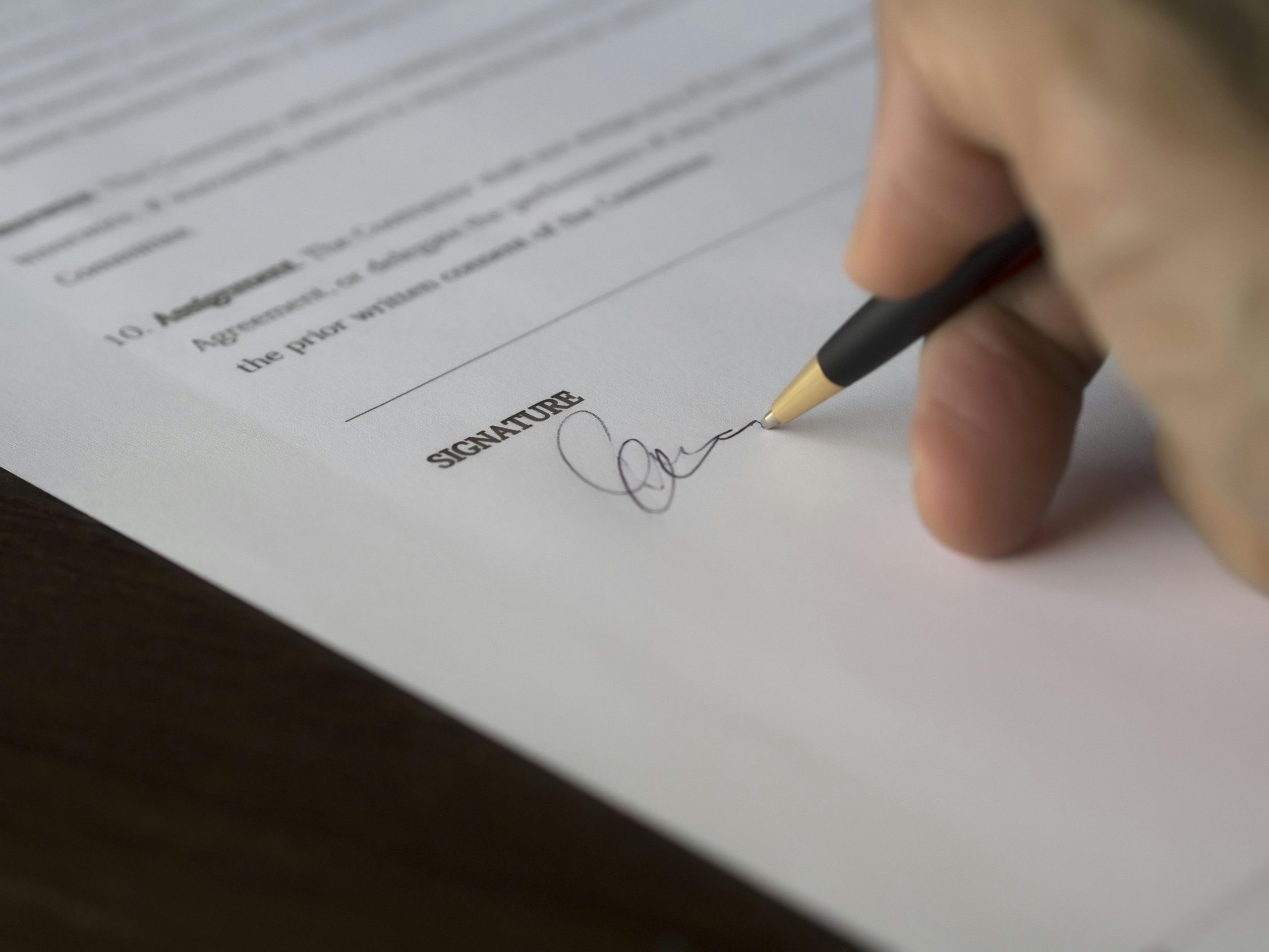 close-up of a hand signing a contract with a pen